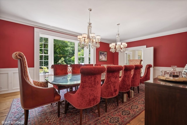 dining room with ornamental molding, a chandelier, wainscoting, and wood finished floors