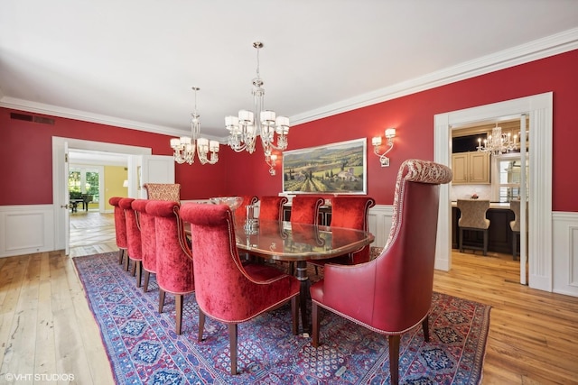 dining space featuring a wainscoted wall, hardwood / wood-style floors, visible vents, and crown molding