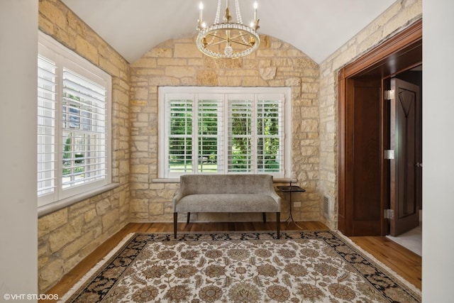 living area with vaulted ceiling, wood finished floors, visible vents, and a notable chandelier