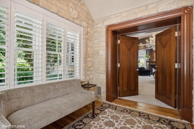 living area featuring visible vents, vaulted ceiling, a wealth of natural light, and a chandelier