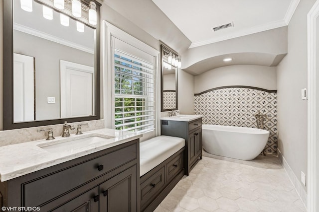 full bath with two vanities, a sink, visible vents, a freestanding bath, and crown molding