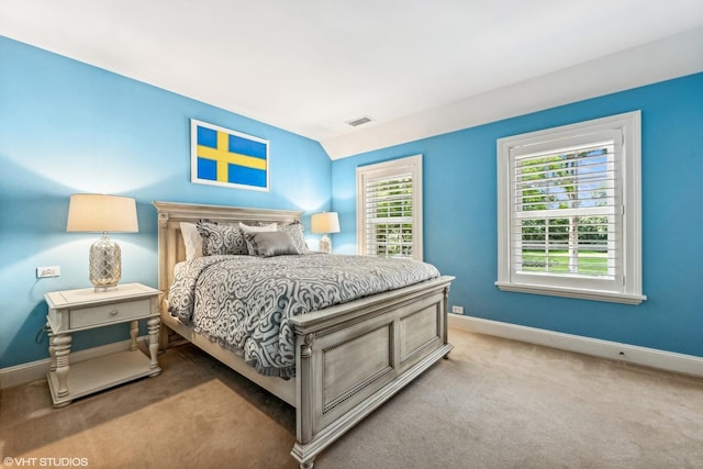 bedroom with lofted ceiling, multiple windows, and light colored carpet