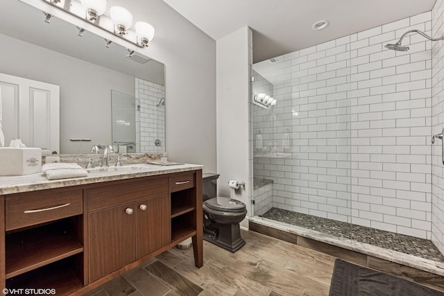 bathroom featuring tiled shower, vanity, and toilet