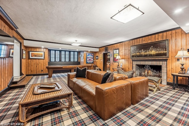 carpeted living room with ornamental molding, a fireplace, wooden walls, and a textured ceiling