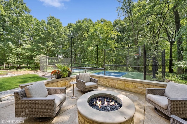 view of patio / terrace with a fire pit, a tennis court, and fence