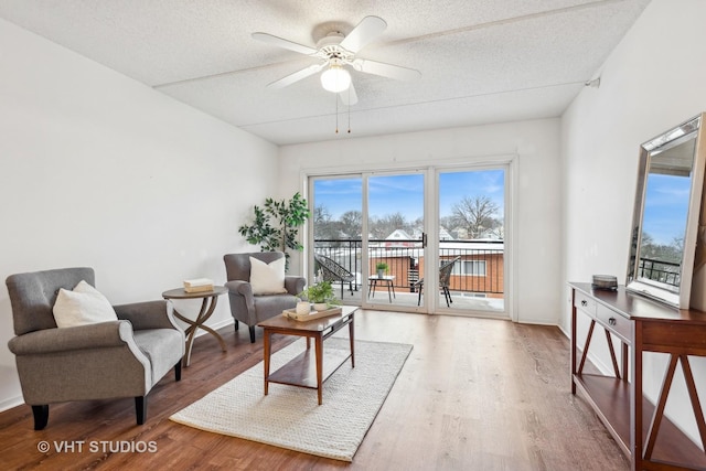 sitting room with ceiling fan, hardwood / wood-style floors, and a textured ceiling