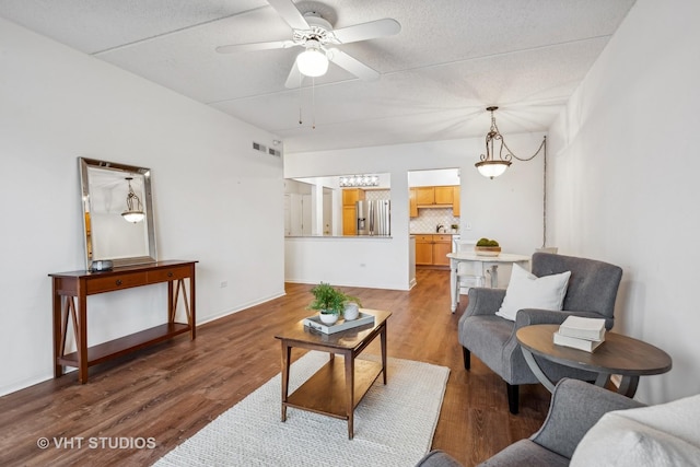 living room with hardwood / wood-style flooring, a textured ceiling, and ceiling fan