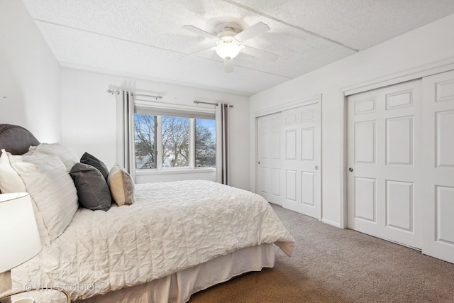 bedroom with multiple closets, ceiling fan, carpet flooring, and a textured ceiling