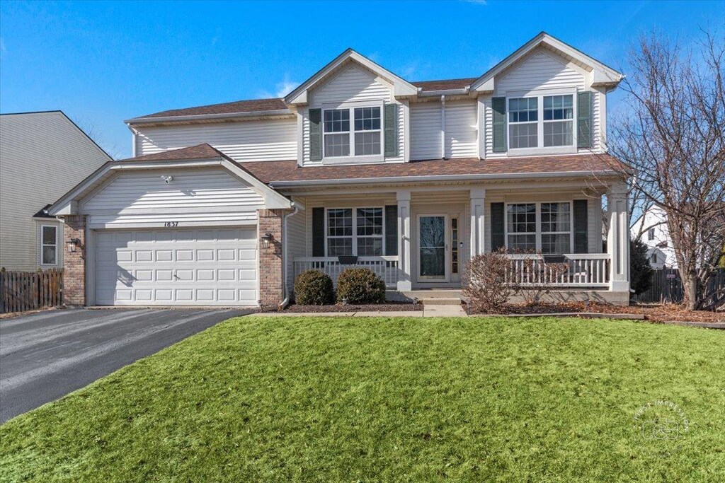 view of front of home with a garage, a front lawn, and a porch