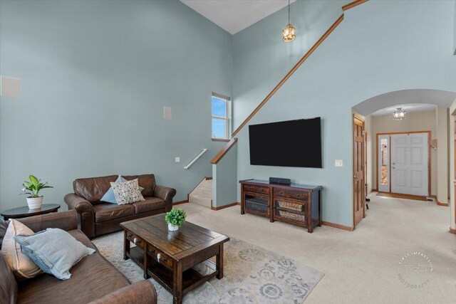 carpeted living room featuring a towering ceiling