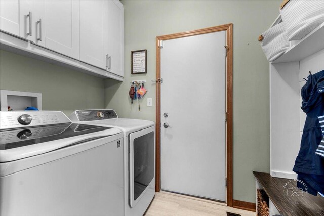 washroom with cabinets, washer and dryer, and light hardwood / wood-style floors