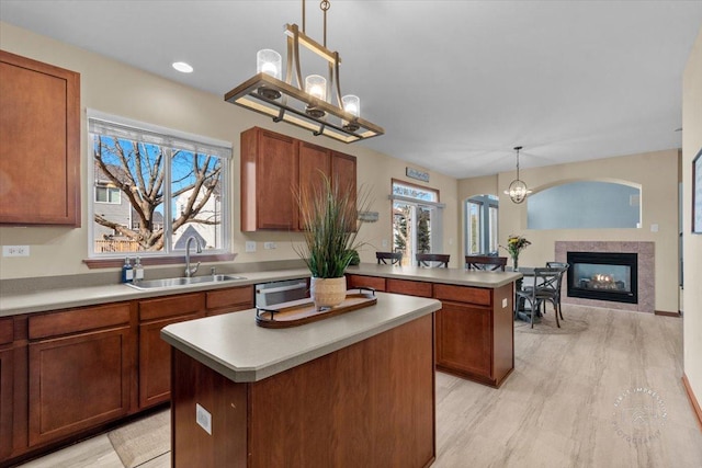 kitchen featuring a kitchen island, sink, hanging light fixtures, light hardwood / wood-style floors, and an inviting chandelier