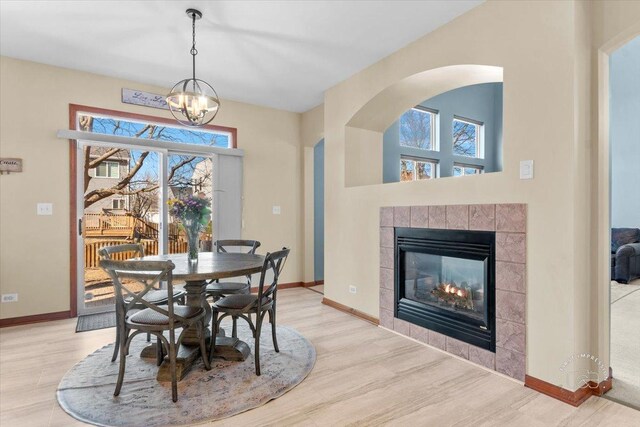 dining space featuring plenty of natural light, a tiled fireplace, and light hardwood / wood-style flooring