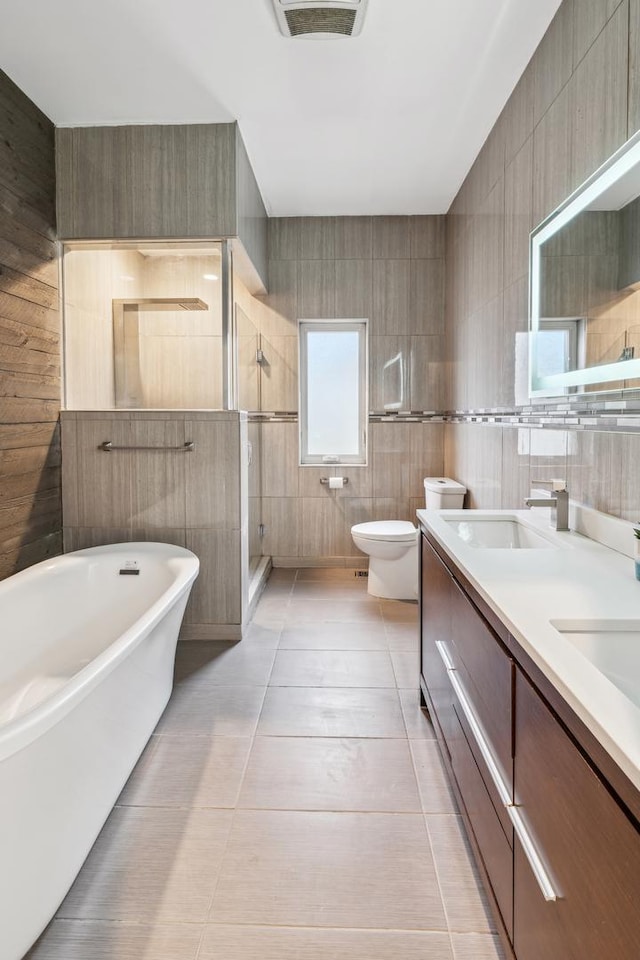 full bathroom featuring shower with separate bathtub, tile walls, toilet, tile patterned floors, and vanity