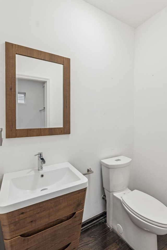 bathroom with toilet, wood-type flooring, and vanity