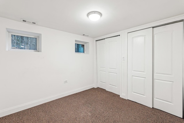 unfurnished bedroom featuring dark colored carpet and multiple closets