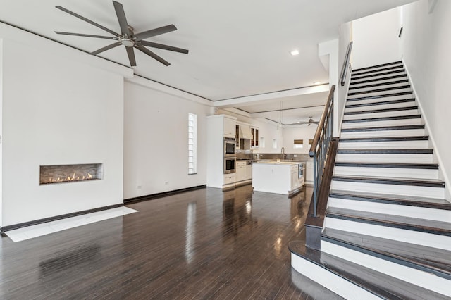 unfurnished living room featuring sink, ceiling fan, and dark hardwood / wood-style floors