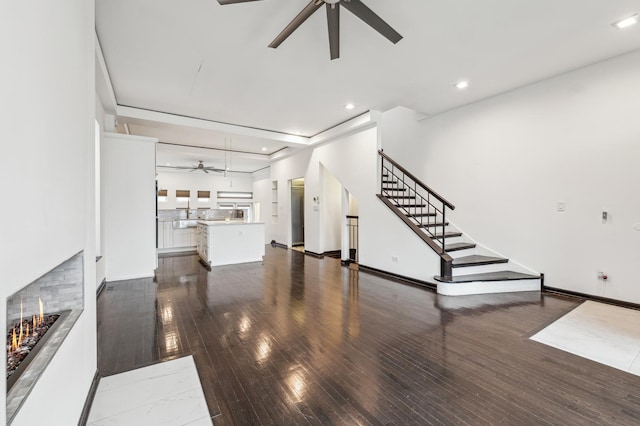 living room featuring ceiling fan and dark wood-type flooring