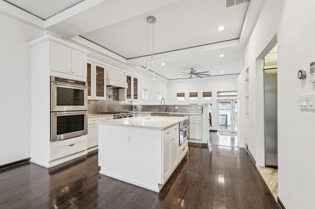 kitchen with white cabinetry, ceiling fan, custom exhaust hood, a kitchen island, and double oven