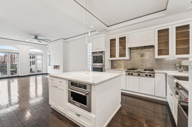 kitchen with stainless steel appliances, light stone countertops, white cabinets, and hanging light fixtures