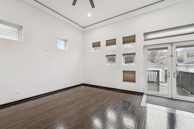 empty room featuring ceiling fan, a wealth of natural light, and dark hardwood / wood-style floors