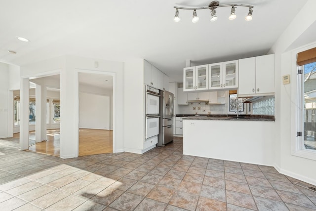 kitchen with stainless steel refrigerator with ice dispenser, white cabinetry, a wealth of natural light, and light tile patterned flooring