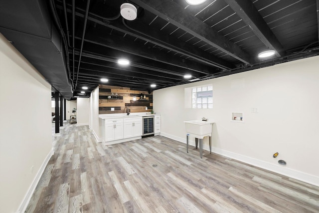 basement with light hardwood / wood-style floors and wine cooler