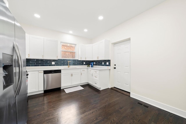 kitchen with white cabinetry, dark hardwood / wood-style flooring, stainless steel appliances, tasteful backsplash, and sink