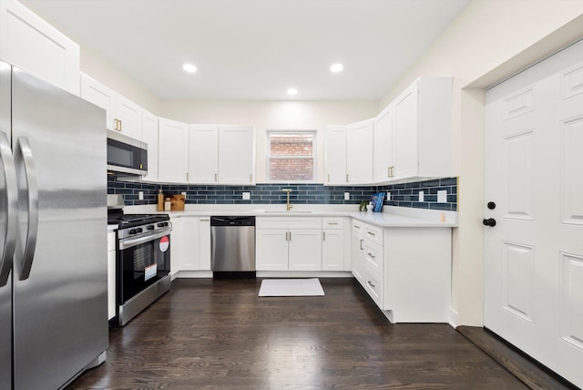 kitchen featuring decorative backsplash, sink, appliances with stainless steel finishes, white cabinets, and dark hardwood / wood-style flooring