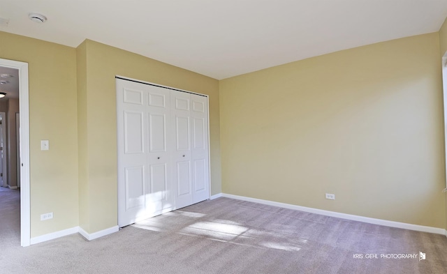 unfurnished bedroom with light colored carpet and a closet