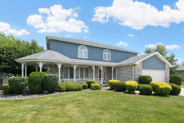 view of front of house with a front yard, covered porch, and a garage