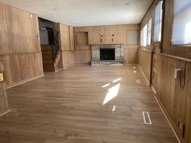 unfurnished living room featuring a fireplace, hardwood / wood-style floors, and wooden walls