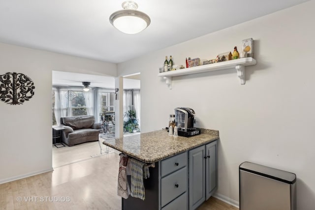 kitchen featuring dark stone counters, ceiling fan, light hardwood / wood-style floors, and gray cabinetry