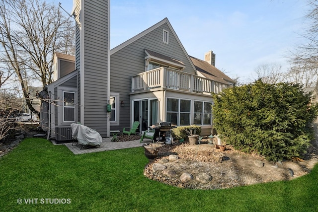 rear view of house featuring a balcony, a patio, and a lawn