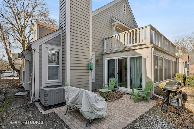 rear view of property with a balcony, a patio area, and central AC unit