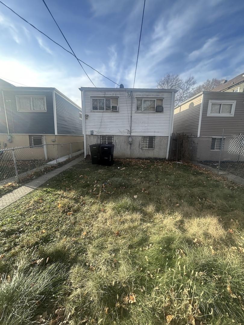 rear view of property featuring central AC and a lawn