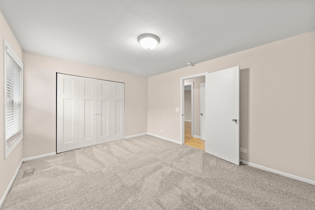 unfurnished bedroom with light colored carpet and a closet