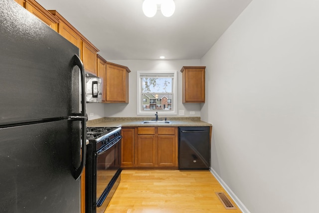 kitchen with sink, light wood-type flooring, and black appliances