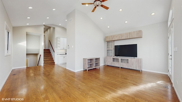 unfurnished living room with ceiling fan, high vaulted ceiling, and wood-type flooring