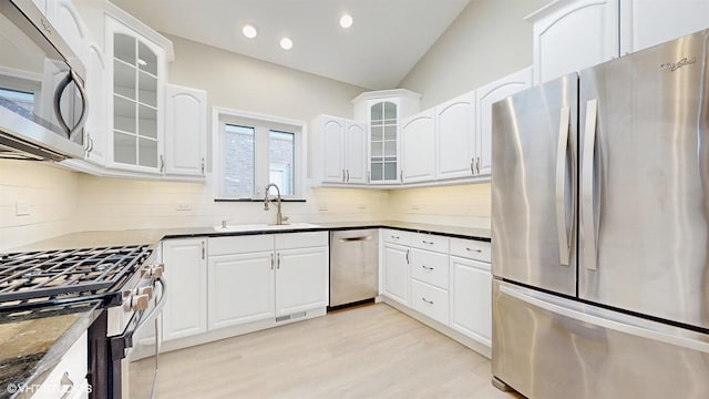 kitchen featuring white cabinetry, stainless steel appliances, dark stone counters, and sink