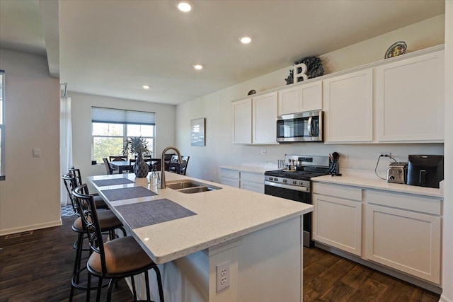 kitchen with dark hardwood / wood-style floors, a center island with sink, white cabinets, appliances with stainless steel finishes, and sink