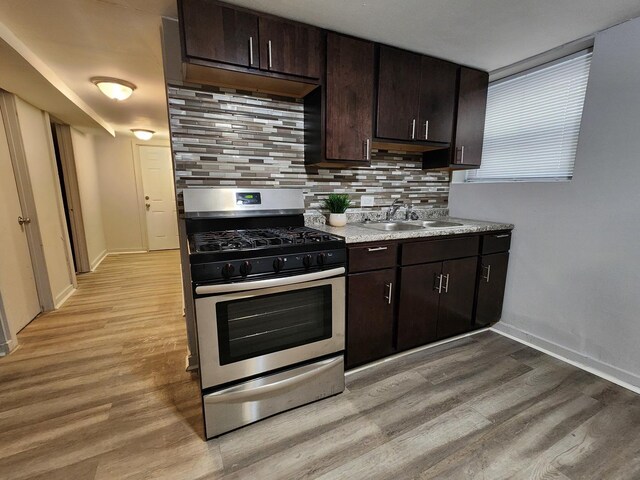 kitchen with appliances with stainless steel finishes, sink, backsplash, light hardwood / wood-style flooring, and dark brown cabinets