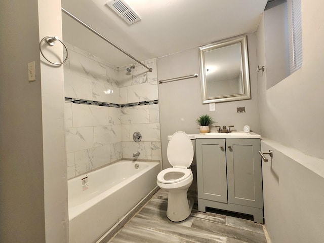 full bathroom with hardwood / wood-style flooring, tiled shower / bath combo, vanity, and toilet