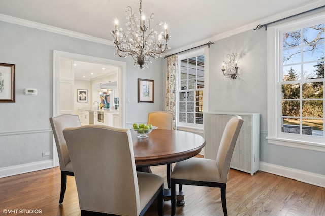 dining room with wood-type flooring, crown molding, and an inviting chandelier