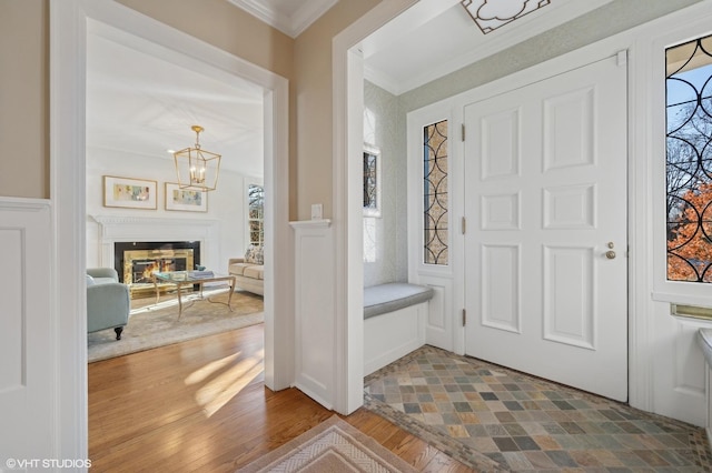 foyer featuring an inviting chandelier, crown molding, and hardwood / wood-style floors