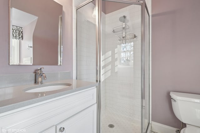 bathroom featuring toilet, a shower with shower door, and vanity