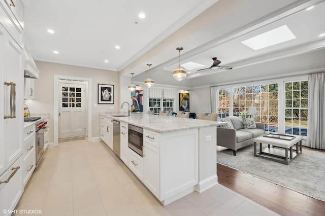 kitchen featuring pendant lighting, white cabinetry, stainless steel appliances, sink, and light stone counters