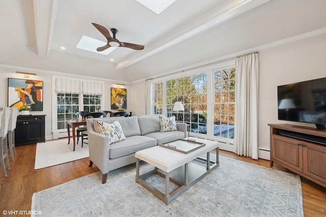 living room featuring a skylight, ceiling fan, baseboard heating, beam ceiling, and light hardwood / wood-style flooring