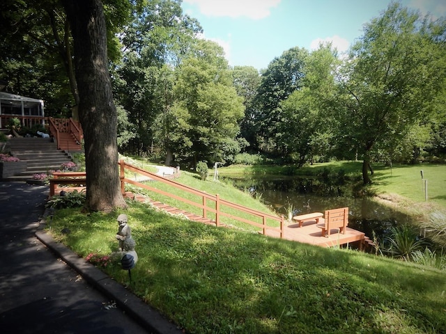 view of home's community with a water view and a lawn