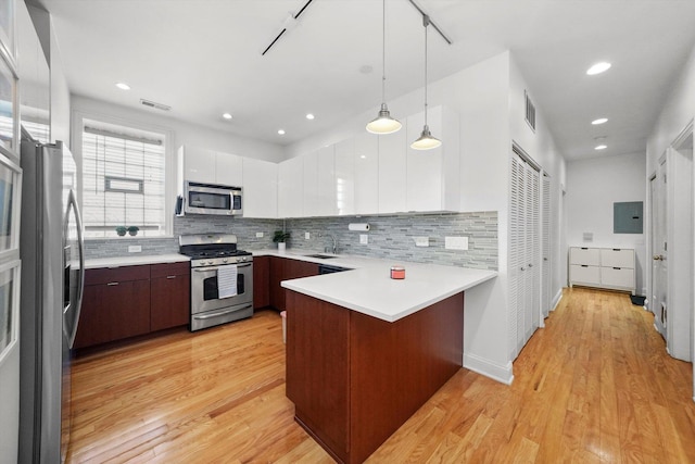 kitchen featuring pendant lighting, stainless steel appliances, sink, kitchen peninsula, and light wood-type flooring